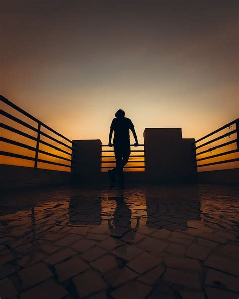 Silhouette of Person Standing on Terrace at Sunset · Free Stock Photo