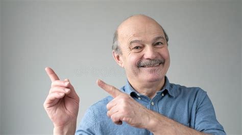 Mature Man With Happy Facial Expression Pointing Aside Presenting