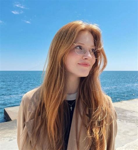 A Woman With Long Hair And Glasses Standing Near The Ocean