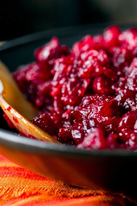 Cranberry Sauce In A Black Bowl With A Wooden Spoon On Top Of It