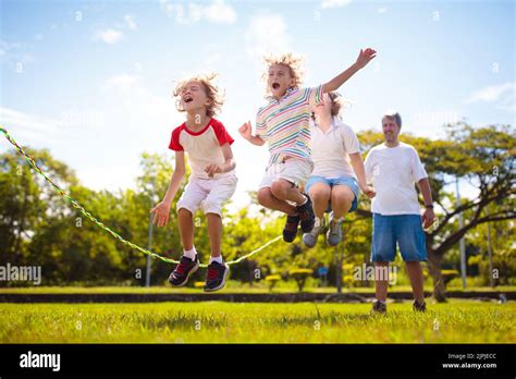 Happy Kids Play Outdoor Children Skipping Rope In Sunny Garden Summer