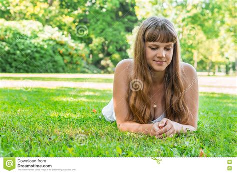 Young Beautiful Woman In White Dress Lying On The Grass Stock Image