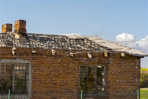 An Old Red Brick House With A Completely Damaged Roof Stock Photo