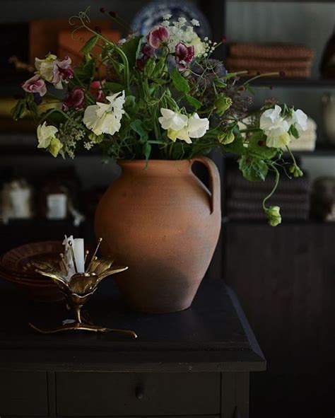 A Vase Filled With Flowers Sitting On Top Of A Table Next To A Candle