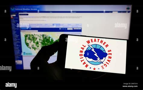 Person Holding Smartphone With Logo Of Us Agency National Weather