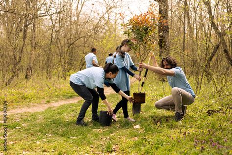 Volunteers And A Child Planting A Tree And Covering Hole In The Ground