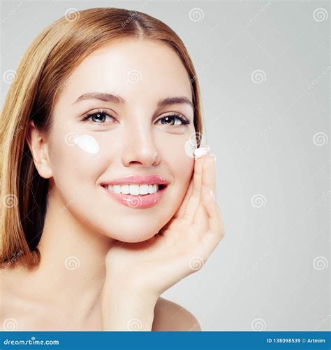 Young Perfect Smiling Woman With Healthy Skin Applying Cream On Her