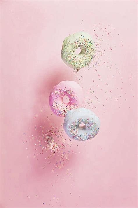 Three Donuts With Sprinkles On A Pink Background