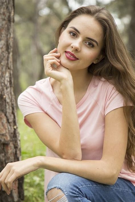 A Woman Sitting In The Woods With Her Hand On Her Chin