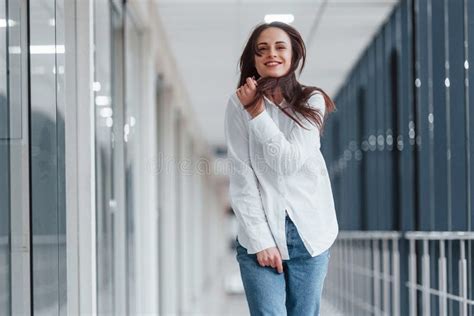 Brunette In White Shirt Indoors In Modern Airport Or Hallway At Daytime