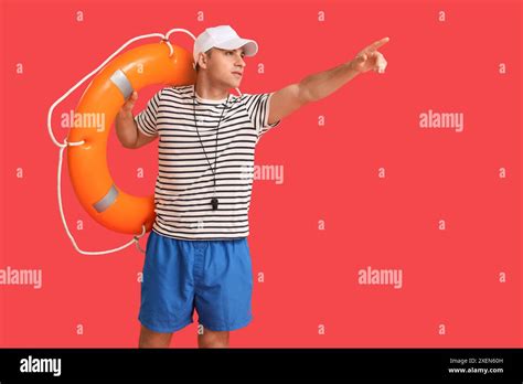 Handsome Male Lifeguard With Ring Buoy Pointing At Something On Red