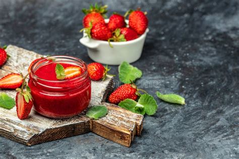 Mermelada De Fresa En El Frasco De Vidrio Con Bayas Frescas Sobre Mesa