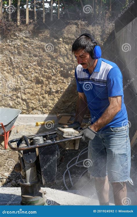 Caucasian Construction Worker Compacting Soil Using A Tamping Rammer