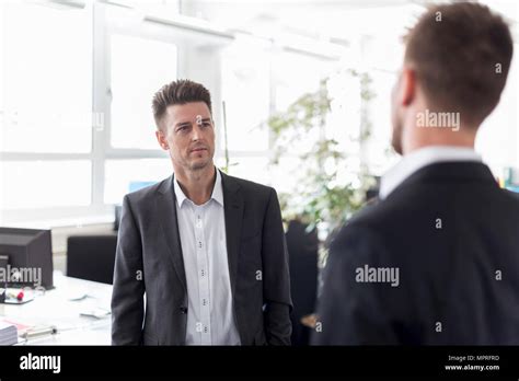 Two Businessmen Standing In Office Discussing Solutions Stock Photo