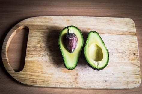 Aguacate Cortado Por La Mitad En Una Tabla De Madera Foto Premium