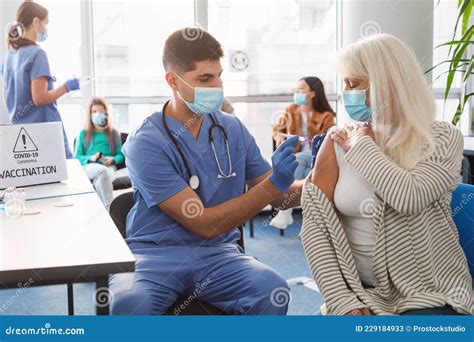 Mature Woman Receiving Coronavirus Vaccine Injection Sitting With