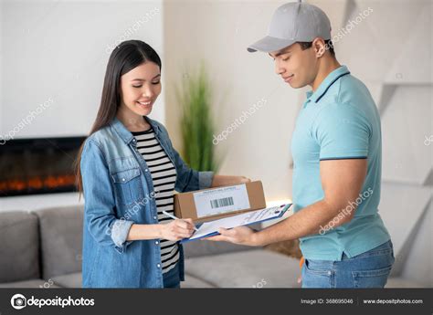 Dark Haired Female Holding Parcel And Signing Delivery Documents Brunette Male Courier Holding