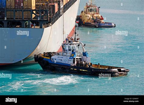 Tugboats Pushing Cargo Ship In The Port Stock Photo Alamy