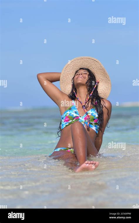 Hispanic Woman Siting On A Beach Wearing A Nice Bikini And Straw Hat