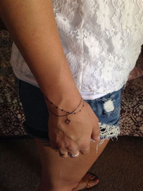 a woman is holding her hand with a tattoo on it's left arm and wearing ...