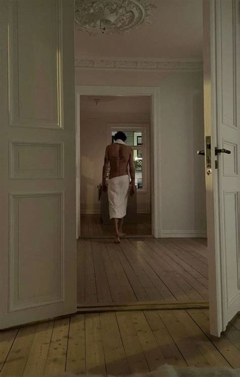 A Woman In A White Dress Is Walking Through An Open Door With Her Back