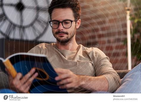 Portrait Of Man Sitting On Couch At Home Reading A Book A Royalty