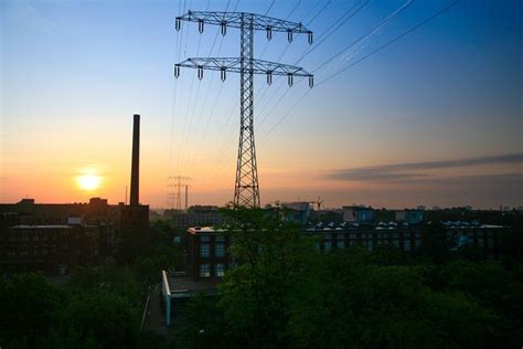 The Sun Is Setting Behind Power Lines In An Area With Tall Buildings