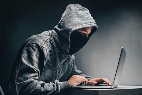 Hacker encapuchado masculino con cara oculta accediendo a información