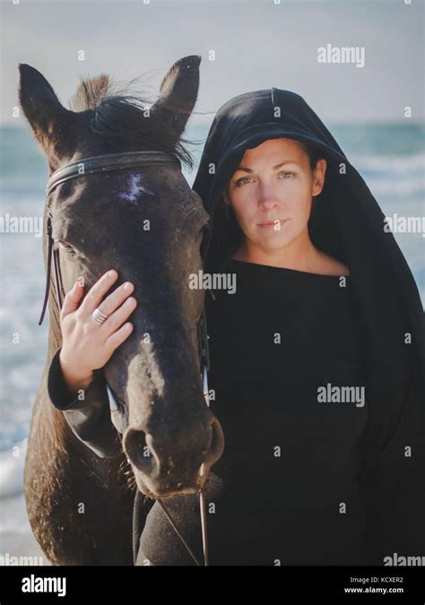 Junge blonde Frau streicheln und umarmen Pferd schöne Dame mit ihren schwarzen Hengst am Meer