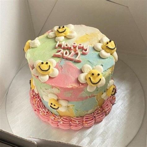 A Birthday Cake Decorated With Smiley Faces And Flowers