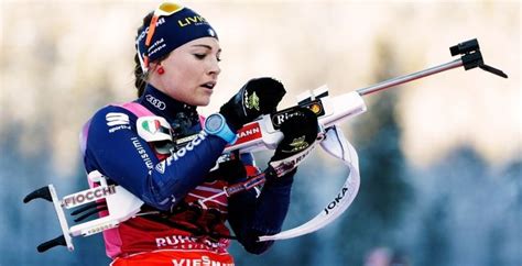 A Female Skier Is Holding Her Skis And Poles In Her Hands As She Looks Down At The Ground