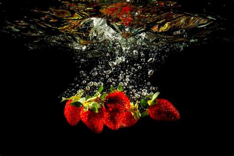 Premium Photo Strawberry Fruit Falling Into The Water Splash Drops