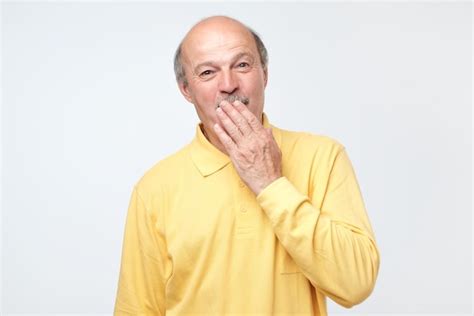 Premium Photo Mature Bald Man Covering Mouth And Laughing