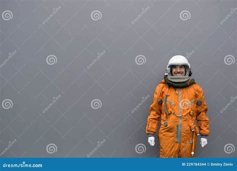 Astronaut Wearing Orange Space Suit and Helmet Standing Against Gray ...