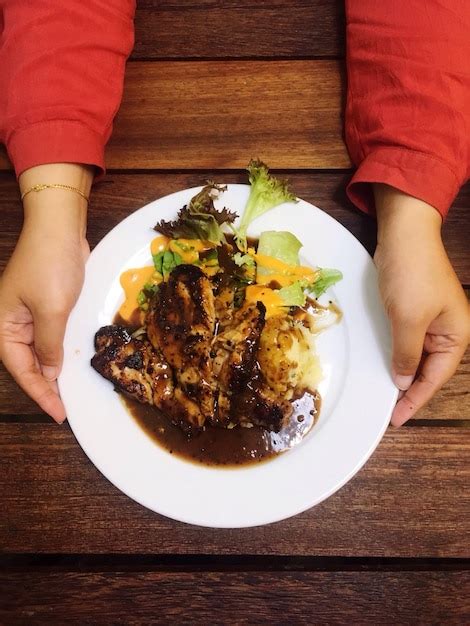 Premium Photo Cropped Hands Holding Food In Plate Over Table