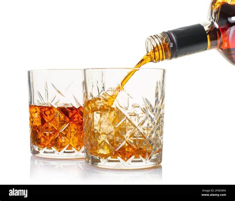 Whiskey Is Poured Into A Glass From Bottle On White Isolated Background