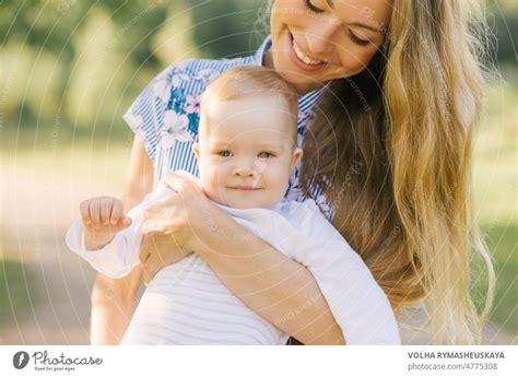 Glückliche Mutter spielt mit ihrem Baby im Arm und lächelt ein