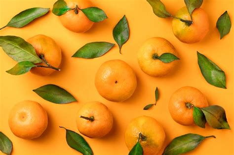 Premium Photo Juicy Mandarins With Leaves On Orange Background