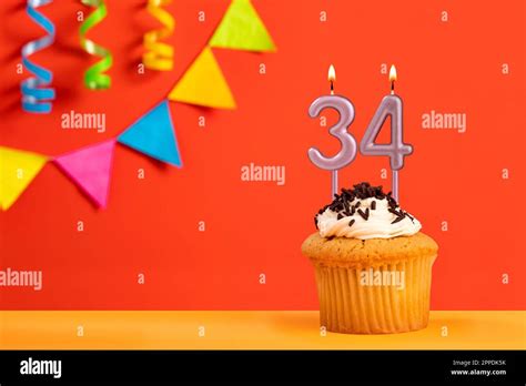 Birthday cake with number 34 candle - Sparkling orange background with ...