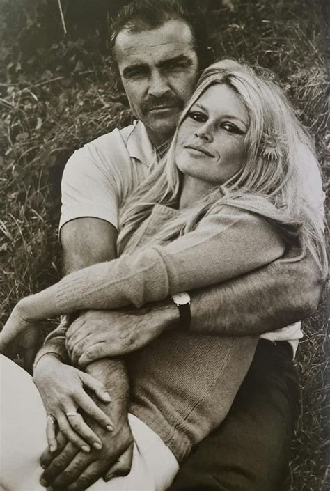 Black And White Photograph Of A Man Holding A Woman S Arm While Sitting