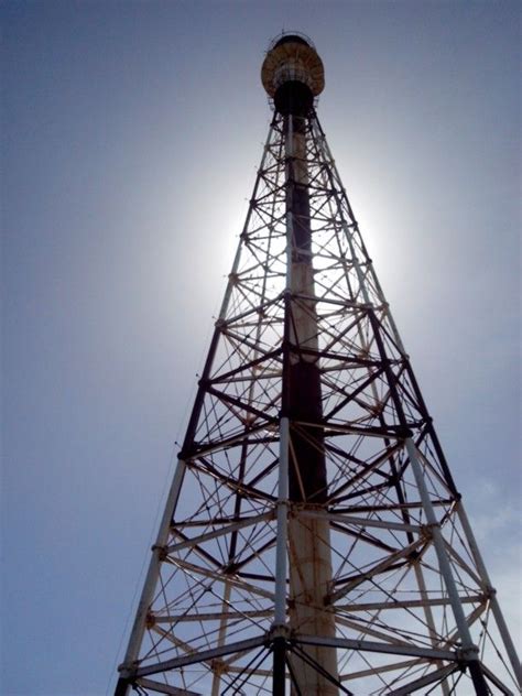 The Sun Shines Brightly Behind A Tall Tower With Wires On It S Sides