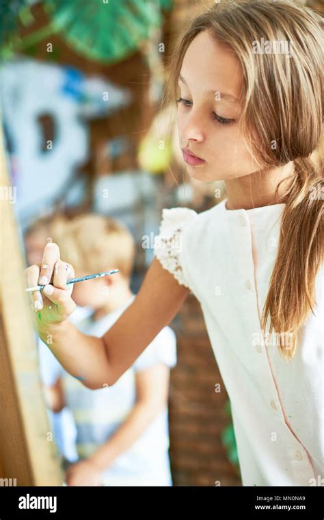 Portrait Of Talented Pretty Girl Painting Picture On Easel In Art Class