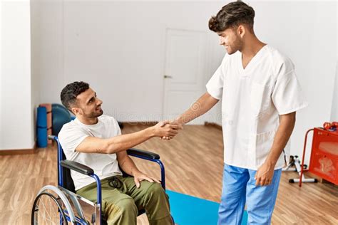 Two Hispanic Men Physiotherapist And Patient Sitting On Wheelchair