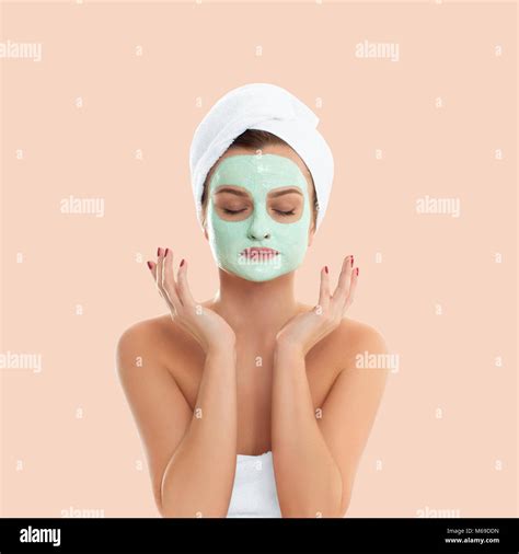 Beautiful Woman Is Getting Facial Clay Mask On Pastel Background