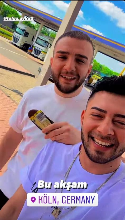 Two Men Standing Next To Each Other In Front Of A Gas Station And One