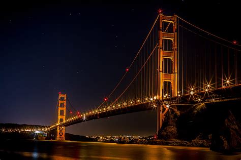 Golden Gate Bridge Over The Bay At Night Illuminated In Gold In San