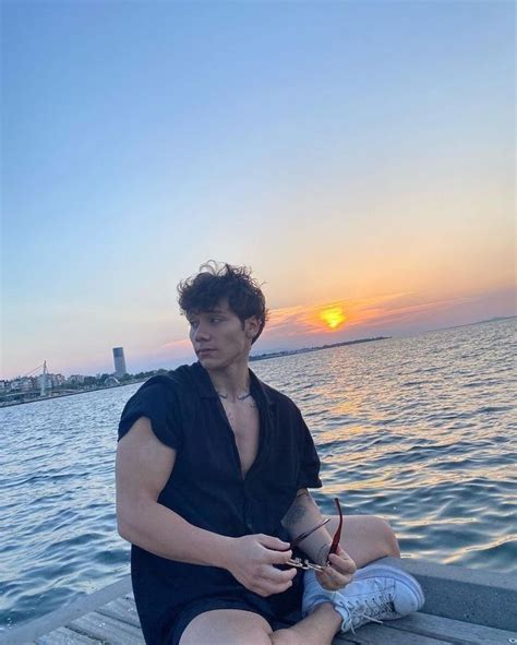 A Man Sitting On The Edge Of A Pier Next To The Ocean With His Arm