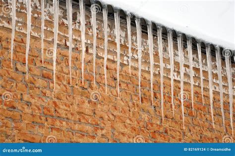 Icicles Hanging From The Roof Of The Old Brick Building Stock Photo