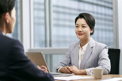 Young Asian Business Woman Conversing With Colleague Businessman In