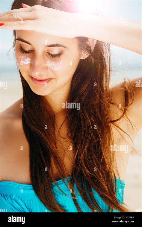 Junge schöne Frau im Bikini mit Sonnencreme in Wangen schützen vor der
